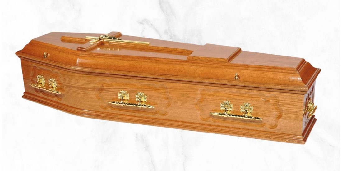 The Somnus medium red oak veneer coffin with cross on the lid and metal handles